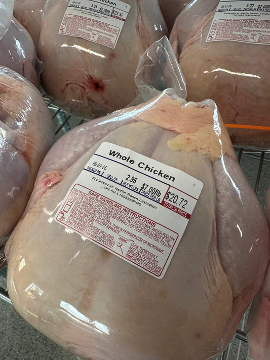 Packaged whole chickens with labels on a metal rack