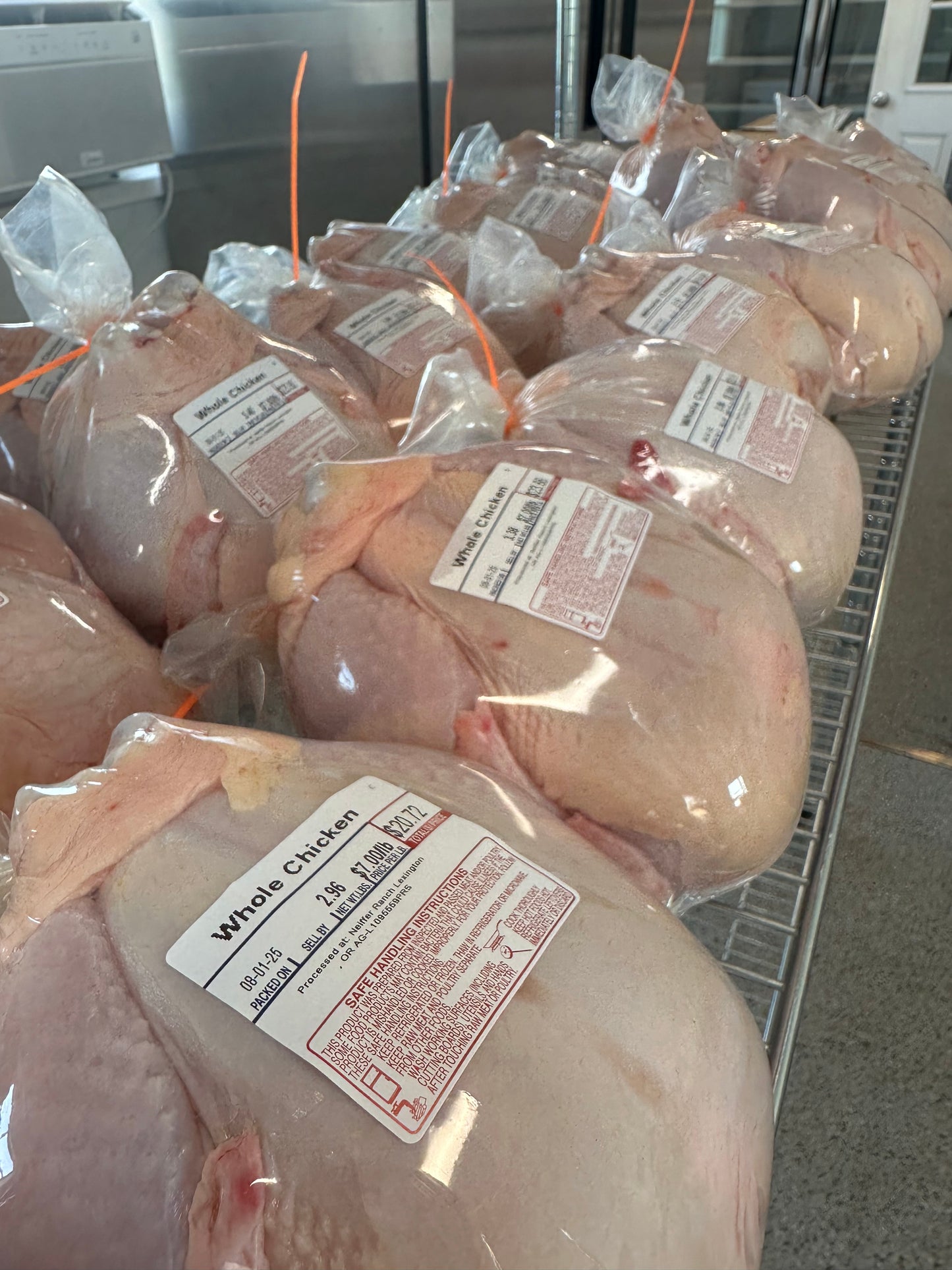 Packed chickens with labels in a refrigerated display case.