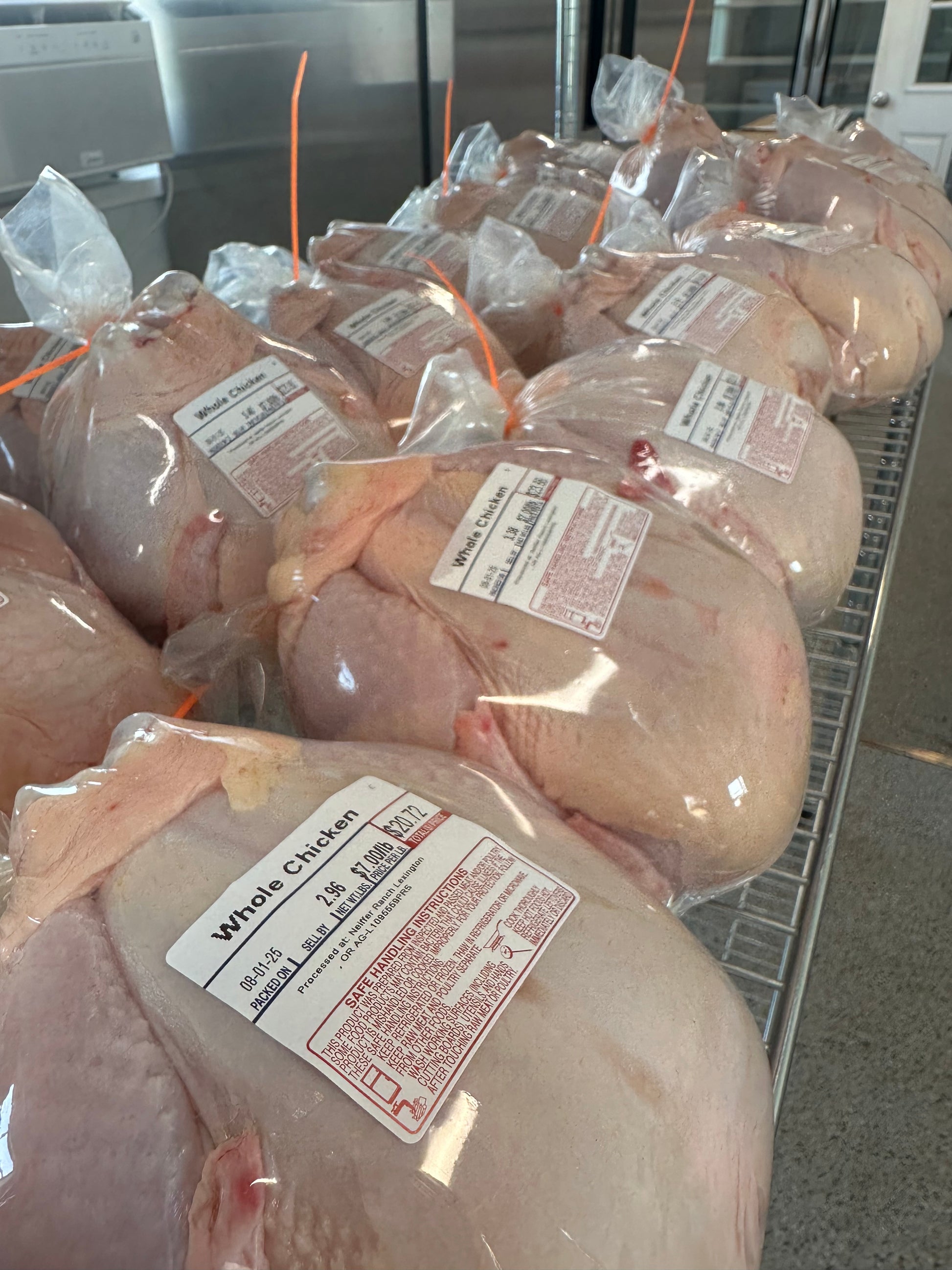 Packed chickens with labels in a refrigerated display case.
